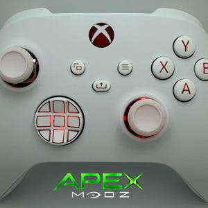 May include: A white video game controller featuring red accents on the central Xbox button, the A, B, X, and Y buttons, and the analog sticks. The controller includes a circular directional pad with a grid pattern and the text APEX MODZ at the bottom.