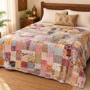 Puede incluir: Una colcha de patchwork que presenta una variedad de parches de tela rectangulares con diversos patrones florales, geométricos y de cachemira. La colcha muestra una paleta multicolor que incluye tonos de rosa, amarillo, azul, rojo y marrón.
