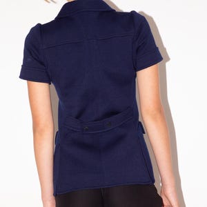 K&ouml;nnte beinhalten: Marineblaue Jacke mit kurzen &Auml;rmeln, Hemdkragen und taillierter Passform. Die Jacke hat einen Knopfverschluss und ein strukturiertes Design. Das Model tr&auml;gt schwarze Shorts. Diese Jacke ist eine stilvolle Erg&auml;nzung f&uuml;r jede Garderobe.