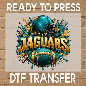 May include: A DTF transfer graphic featuring a teal football helmet and a football with gold accents, surrounded by teal and gold paint splatters. The word JAGUARS is written in bold gold lettering across the center. The text READY TO PRESS DTF TRANSFER is displayed above and below the central design.