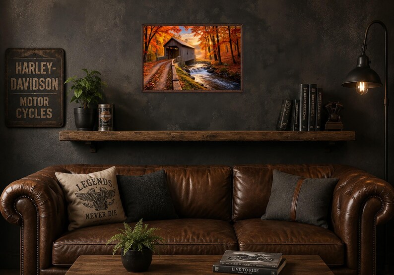 Op de afbeelding: Een rechthoekige wandkunstprint met een overdekte brug over een stromende beek, omringd door levendige oranje en gele herfstbomen. De sc&egrave;ne is vastgelegd in warm, goudkleurig licht en toont een zandpad dat naar de houten structuur leidt.