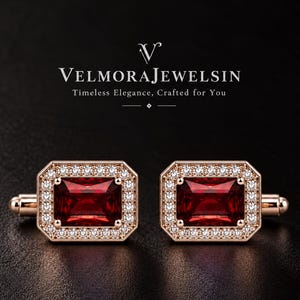May include: A pair of rose gold cufflinks featuring a rectangular red gemstone center surrounded by a halo of small white stones. The text VelmoraJewelsin Timeless Elegance, Crafted for You is displayed above the cufflinks.