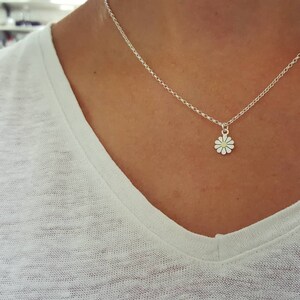 A silver chain necklace with a small silver daisy pendant.