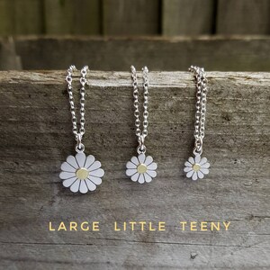 Three silver necklaces with daisy pendants. The daisies are silver with a gold center. The necklaces are arranged from left to right in order of size: large, little, teeny. The text below the necklaces reads: 'LARGE LITTLE TEENY'.