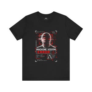 May include: A black short-sleeve t-shirt featuring a graphic print of a distorted human silhouette with red glitch effects. The design includes the text "MACHINE VISION ERROR" and various technical data labels in white and red on the chest.