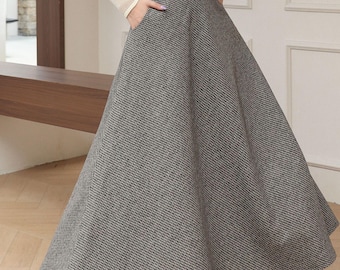 May include: A long, flared skirt in a black and white houndstooth pattern. The skirt is paired with a cream-colored sweater with a sheer neckline and sleeves. The outfit is suitable for a variety of occasions.