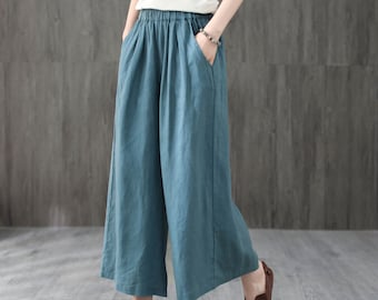 May include: Teal wide-leg linen pants with an elastic waistband. The pants are cropped and have pockets on the sides.