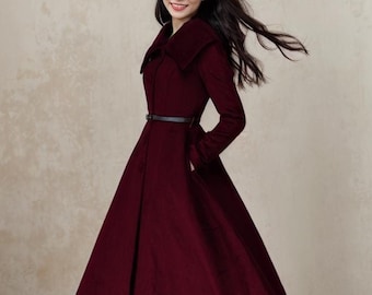 Peut inclure: Un manteau mi-long bordeaux avec un col large, une ceinture noire et des manches longues. Le manteau a une jupe évasée et est porté avec des bottines noires.