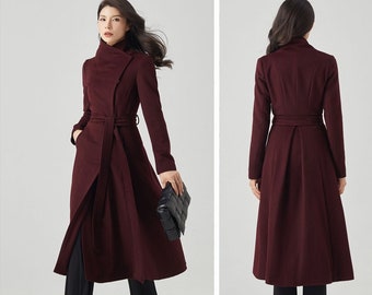 Peut inclure: Un long manteau en laine bordeaux avec un col montant, une ceinture et une jupe légèrement évasée.