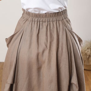 May include: A brown linen skirt with a wide elastic waistband and two large pockets on the sides.