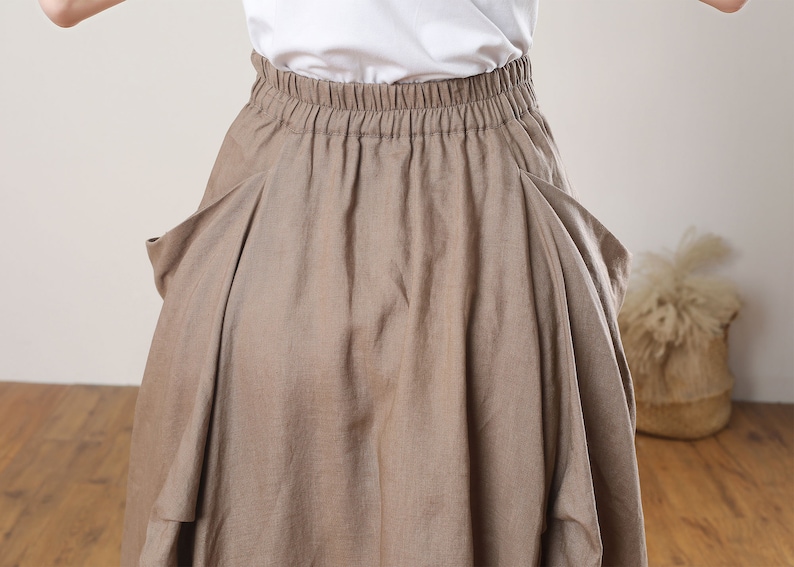 May include: A brown linen skirt with a wide elastic waistband and two large pockets on the sides.