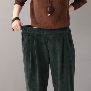 May include: Green corduroy pants with a wide leg and a high waist. The pants have a relaxed fit and are made of a soft, comfortable fabric.