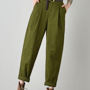 Op de afbeelding: Groene broek met hoge taille, een bruine leren riem en bruine leren laarzen.