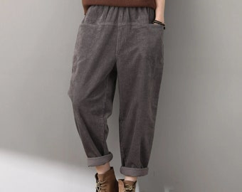 May include: Gray corduroy pants with a wide leg and a relaxed fit. The pants have a drawstring waistband and two pockets.