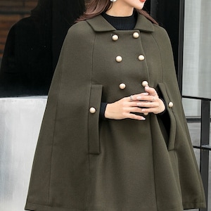 May include: A dark green double-breasted cape with gold buttons. The cape has a collar and long sleeves.