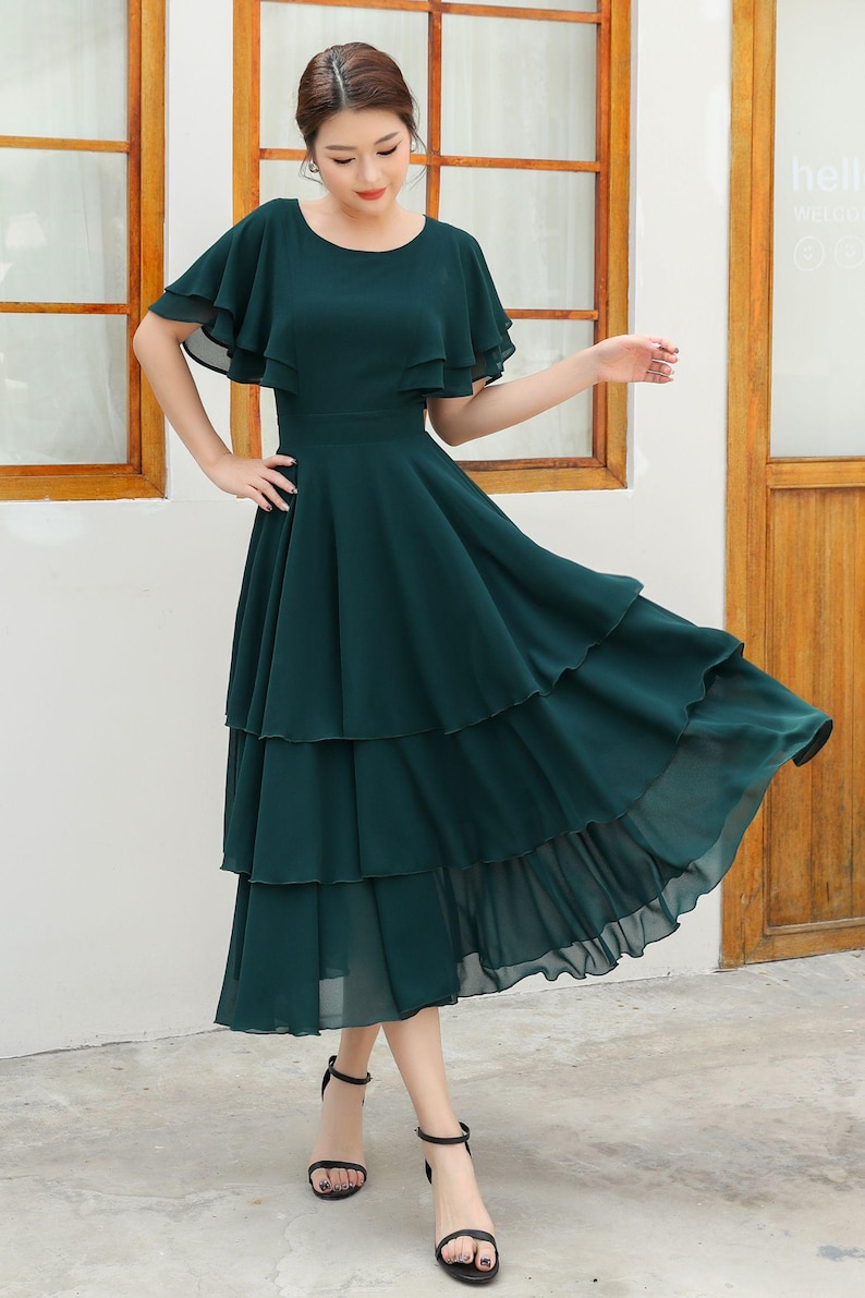 May include: A dark green tiered maxi dress with a ruffled neckline and short sleeves.