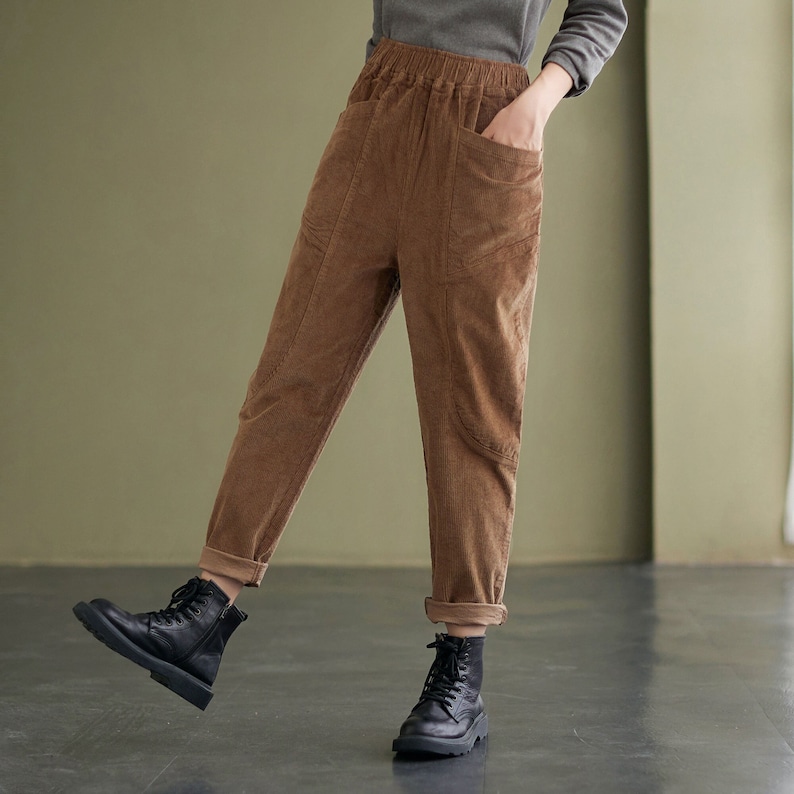 May include: Brown corduroy trousers with a relaxed fit and a drawstring waist. The trousers have large pockets on the front and are cuffed at the ankles.