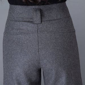 Puede incluir: Pantalones grises de cintura alta, de pierna ancha y con trabillas para el cintur&oacute;n.