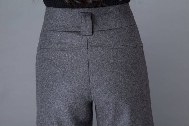 Puede incluir: Pantalones grises de cintura alta, de pierna ancha y con trabillas para el cintur&oacute;n.