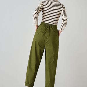 Op de afbeelding: Een olijfgroene, hoge broek met een trekkoord in de taille en gezoomde pijpen. De broek is gemaakt van een lichtgewicht stof en heeft een ontspannen pasvorm.
