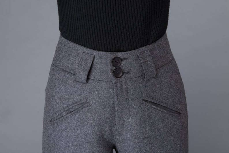 Puede incluir: Pantal&oacute;n de lana gris con cierre de doble bot&oacute;n y dos bolsillos delanteros.
