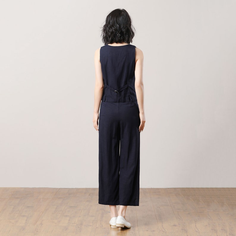May include: A sleeveless navy blue jumpsuit with a wide leg and a button closure at the back.