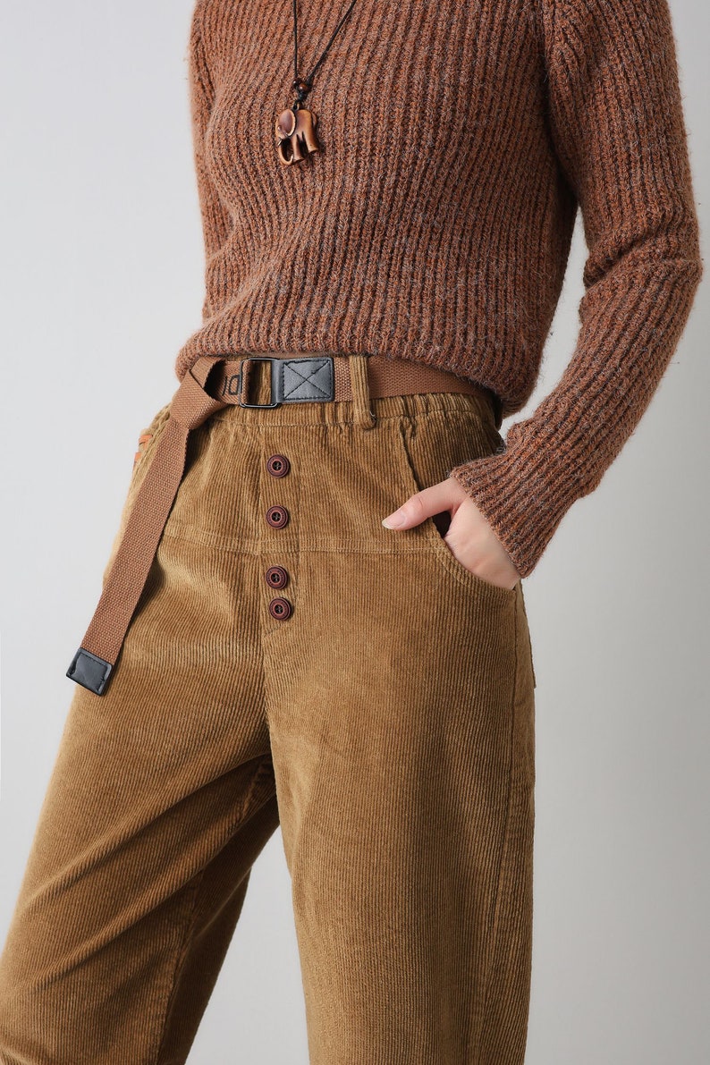 K&ouml;nnte beinhalten: Braune Cordhose mit Knopfleiste und braunem Stoffg&uuml;rtel. Die Hose hat eine lockere Passform und ist aus einem weichen, bequemen Material gefertigt.