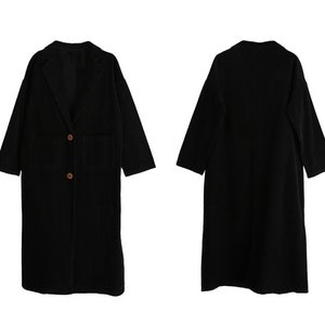 May include: A black long-sleeved coat with a collar and two buttons. The coat has a pocket on the left side.