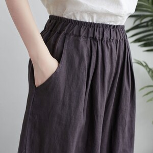 Puede incluir: Un pantal&oacute;n de lino gris oscuro de pierna ancha y cintura el&aacute;stica.