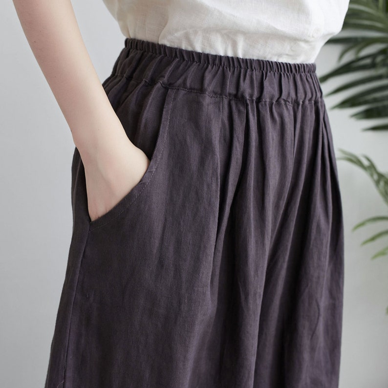 Puede incluir: Un pantal&oacute;n de lino gris oscuro de pierna ancha y cintura el&aacute;stica.