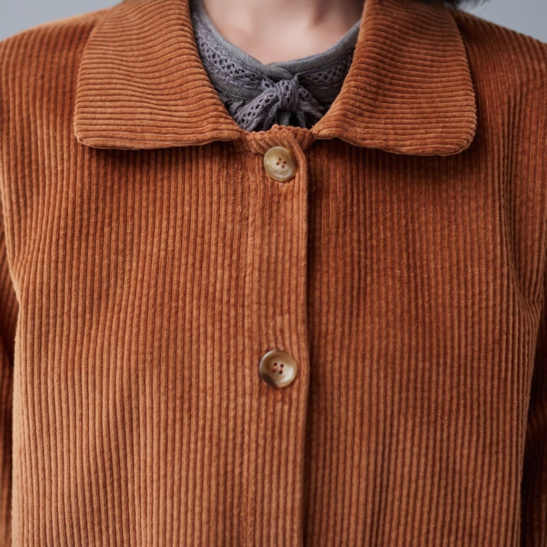 Pu&ograve; includere: Una giacca di velluto a coste marrone con colletto e chiusura con bottoni. La giacca ha una texture a coste e una vestibilit&agrave; leggermente oversize.