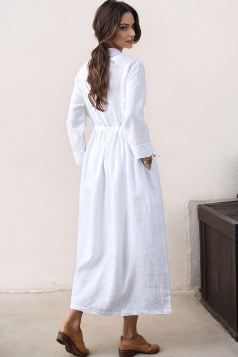 May include: A white long-sleeved linen dress with a drawstring waist and pockets. The dress is flowy and has a relaxed fit.