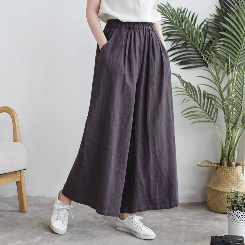 Puede incluir: Un pantal&oacute;n de lino gris oscuro de pierna ancha, cintura alta y corte holgado. El pantal&oacute;n tiene un dise&ntilde;o sencillo sin adornos.