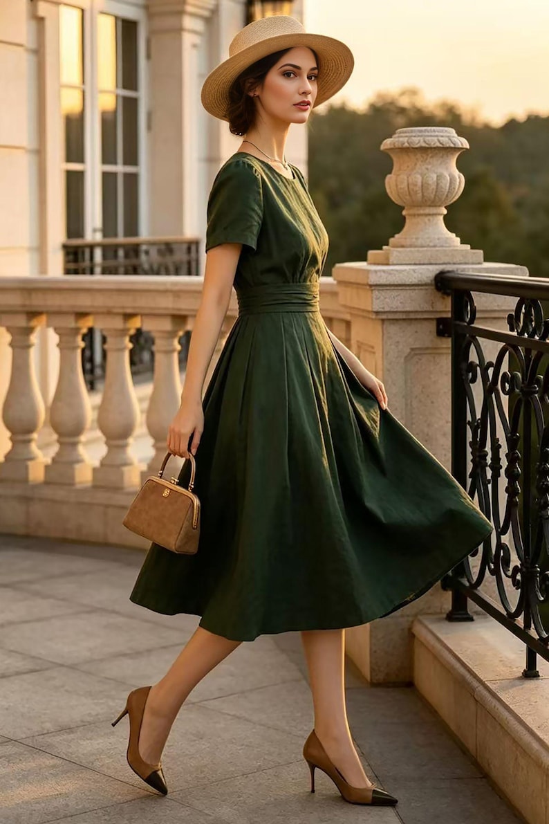 May include: A dark green midi dress with short sleeves, a round neckline, and a fitted waist. The dress is paired with a tan straw hat, a small brown structured handbag with a gold clasp, and tan high-heeled pumps with black pointed toes.
