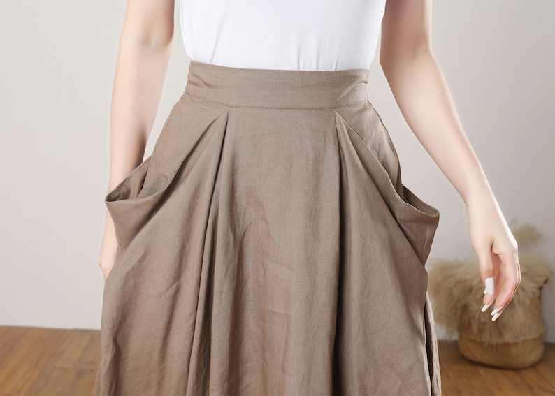 May include: A brown linen skirt with large pockets on the sides. The skirt has a high waist and a flowing silhouette.