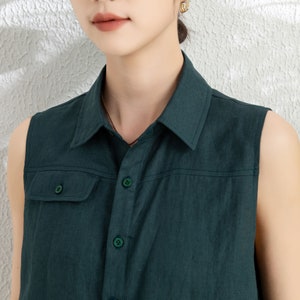 May include: A dark green sleeveless shirt with a button-up front and a single pocket on the left chest.