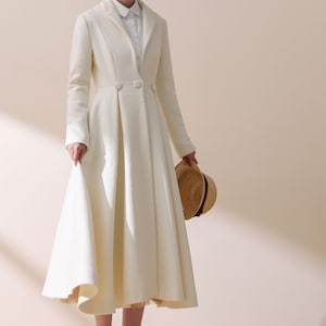 May include: A white long-sleeved coat with a flared skirt and a single button closure. The coat is made of a soft, luxurious fabric and has a classic, elegant style.