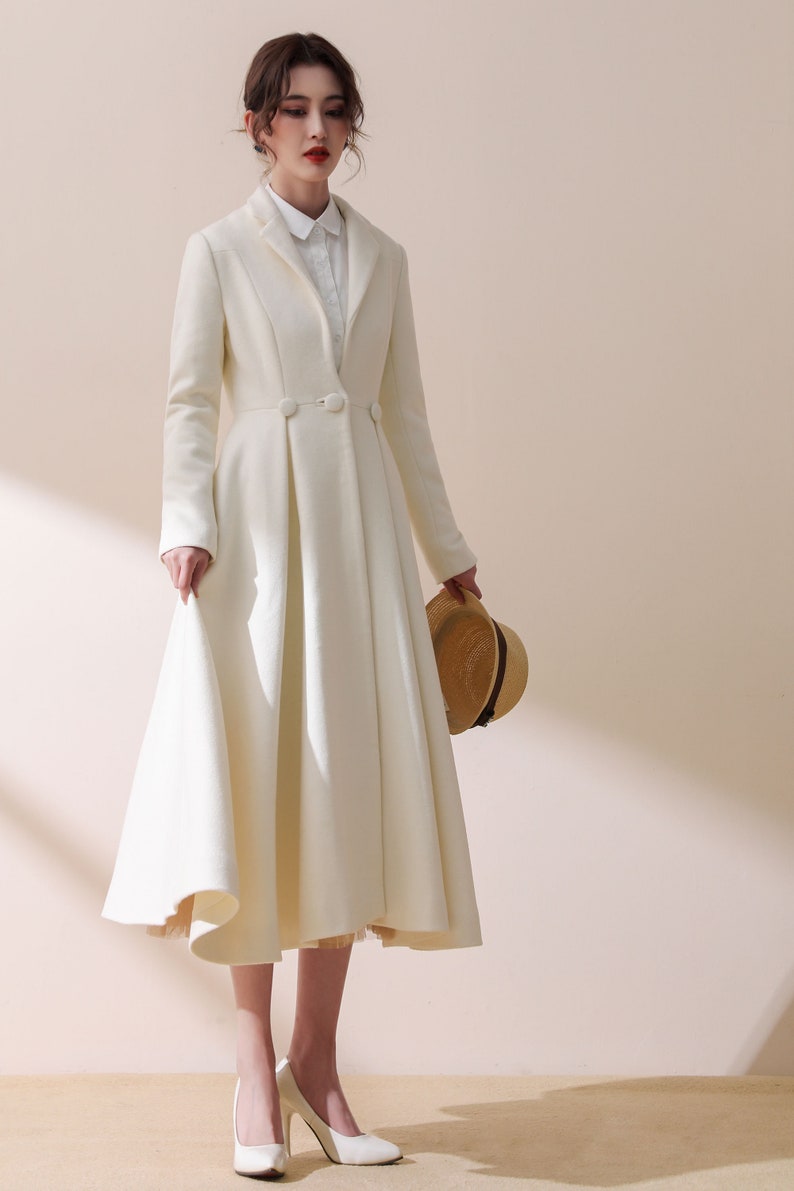 May include: A white long-sleeved coat with a flared skirt and a single button closure. The coat is made of a soft, luxurious fabric and has a classic, elegant style.