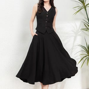Peut inclure: Un gilet noir sans manches avec un col en V et une fermeture &agrave; boutons, port&eacute; avec une jupe noire &eacute;vas&eacute;e. La tenue est port&eacute;e par une femme aux cheveux longs et fonc&eacute;s et des chaussures brunes.