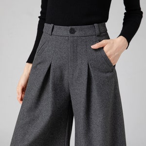 Pu&ograve; includere: Pantaloni larghi a vita alta, di colore grigio, con pieghe e orlo corto. I pantaloni hanno una chiusura con bottone e tasche.