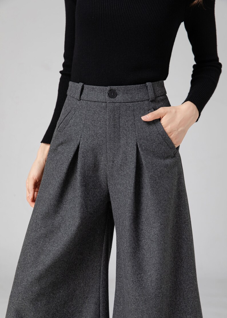 Pu&ograve; includere: Pantaloni larghi a vita alta, di colore grigio, con pieghe e orlo corto. I pantaloni hanno una chiusura con bottone e tasche.