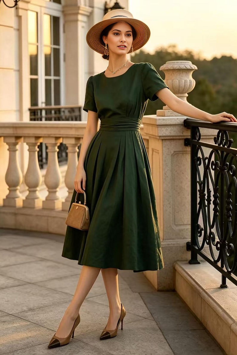 May include: A dark green midi dress with short sleeves, a round neckline, and a pleated skirt with a cinched waist. The outfit includes a tan straw hat, a small brown structured handbag, and two-tone tan and black pointed-toe high heel pumps.