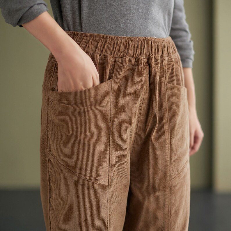 May include: Brown corduroy trousers with a drawstring waist and large pockets. The trousers have a relaxed fit and are made of a soft, comfortable fabric.