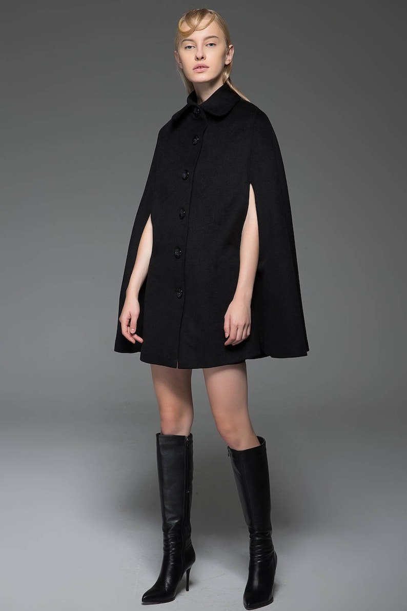 May include: A black wool cape with a button-up front and long sleeves. The cape is knee-length and has a wide, flowing silhouette.