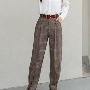K&ouml;nnte beinhalten: Ein wei&szlig;es Hemd mit Knopfleiste, eine braune karierte Hose und ein brauner Lederg&uuml;rtel. Die Hose hat eine Faltenfront und ist an den Kn&ouml;cheln geb&uuml;ndelt. Braune Lederstiefel vervollst&auml;ndigen das Outfit.