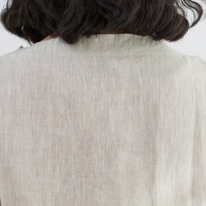 Pode incluir: Uma blusa de linho bege claro lisa com decote redondo.