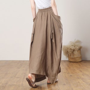May include: A brown linen skirt with a gathered waist and large pockets. The skirt is long and flowy, and it has a casual, relaxed look.