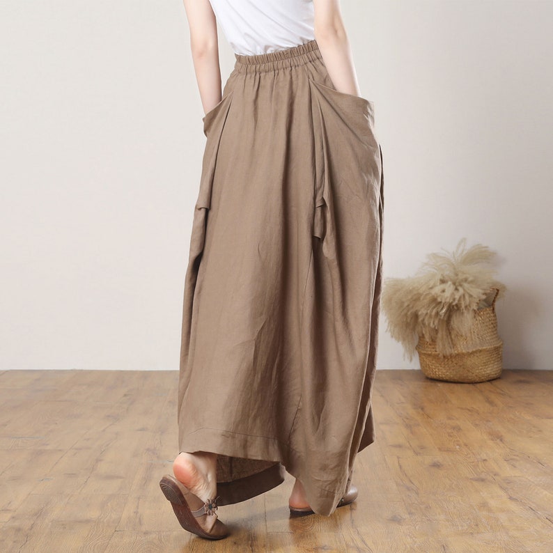 May include: A brown linen skirt with a gathered waist and large pockets. The skirt is long and flowy, and it has a casual, relaxed look.