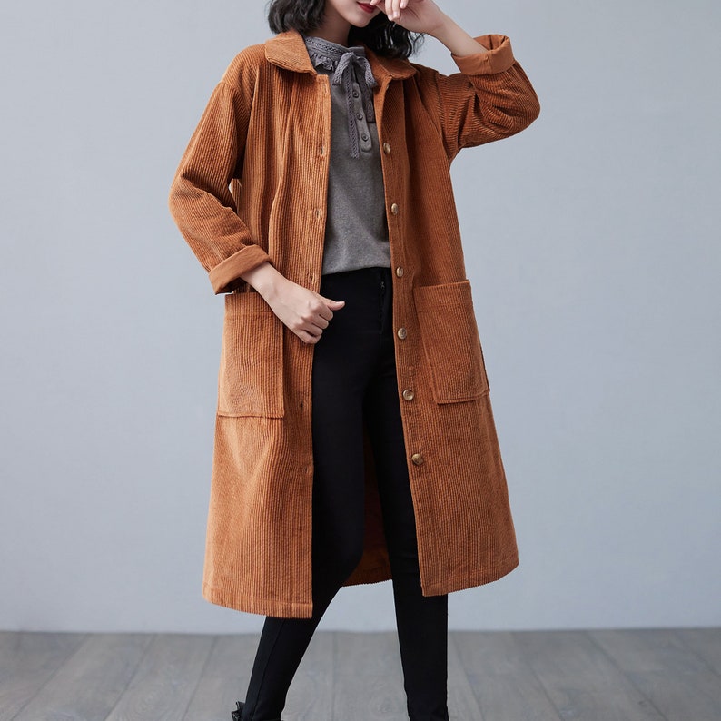 Pu&ograve; includere: Un lungo cappotto di velluto a coste marrone con chiusura a bottoni e due grandi tasche. Il cappotto ha un colletto ed &egrave; sfoderato.