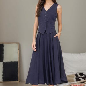 Peut inclure: Un gilet sans manches bleu marine avec un col en V et une fermeture &agrave; boutons, associ&eacute; &agrave; une jupe midi bleu marine assortie. La jupe a une silhouette &eacute;vas&eacute;e et des poches.